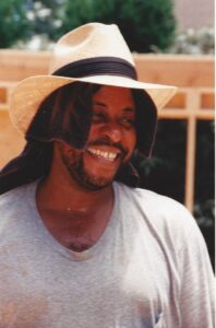 Younger Elijah Price on a construction site with a hat and towel to keep the sun off his head and neck.
