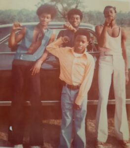 Four brothers pose in front of a car in the 1970s