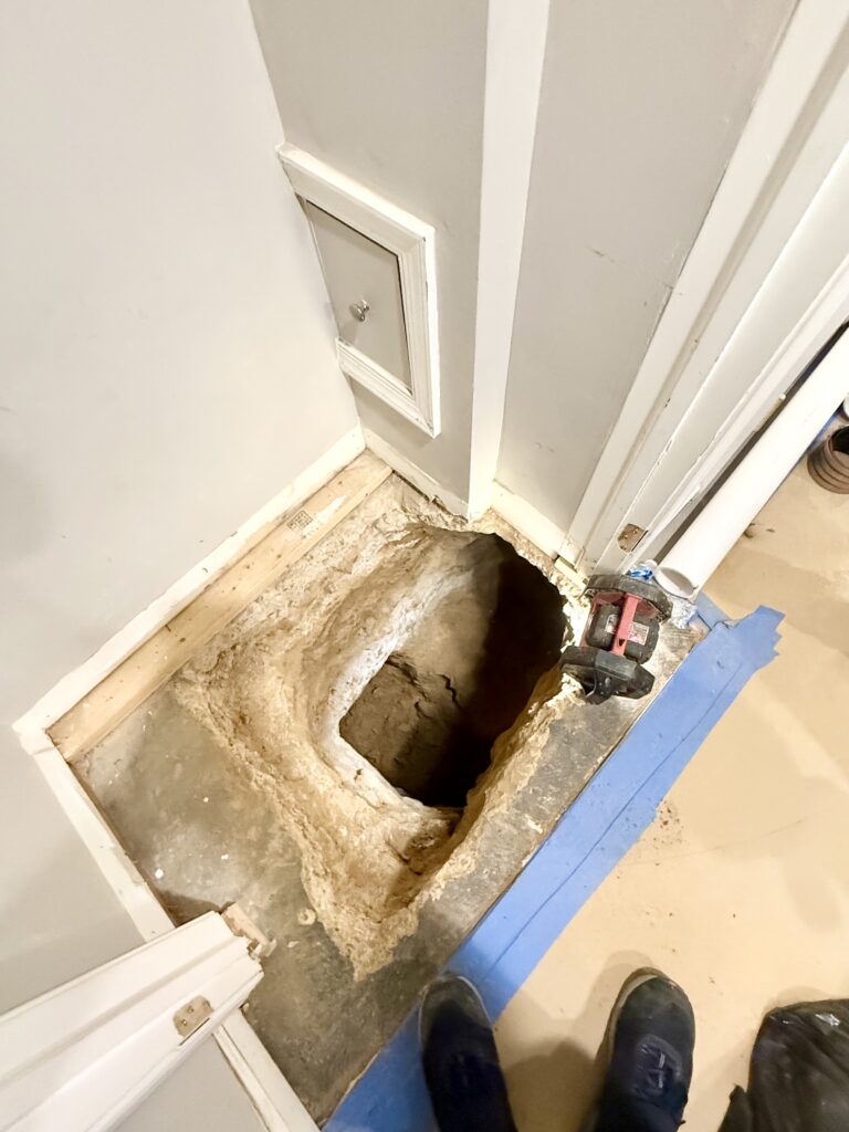 photo showing hole drilled through concrete where new row house powder room floor will go. hole will eventually have plumbing lines running through it.