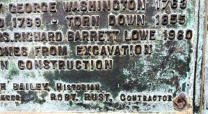Close-up of a historic plaque in Alexandria referencing George Washington’s Town House and later reconstruction work by Robt. Rust, contractor