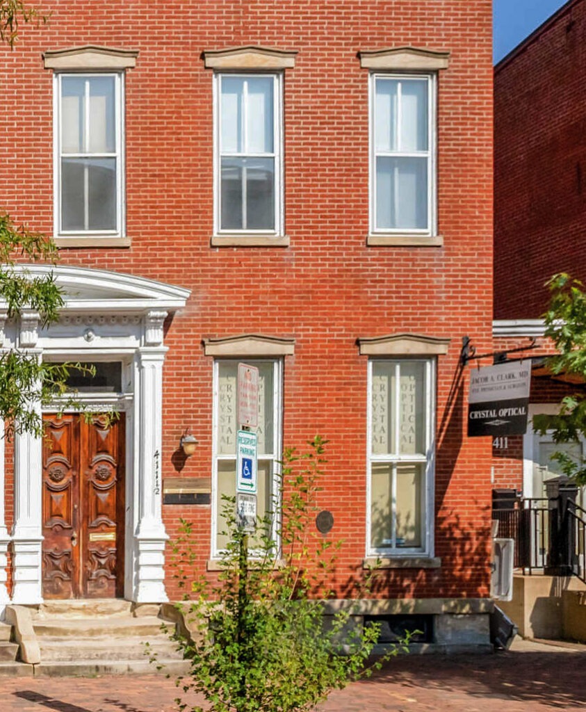Historic brick façade in Old Town Alexandria with tall narrow windows, decorative window crowns, and an ornate entry surround