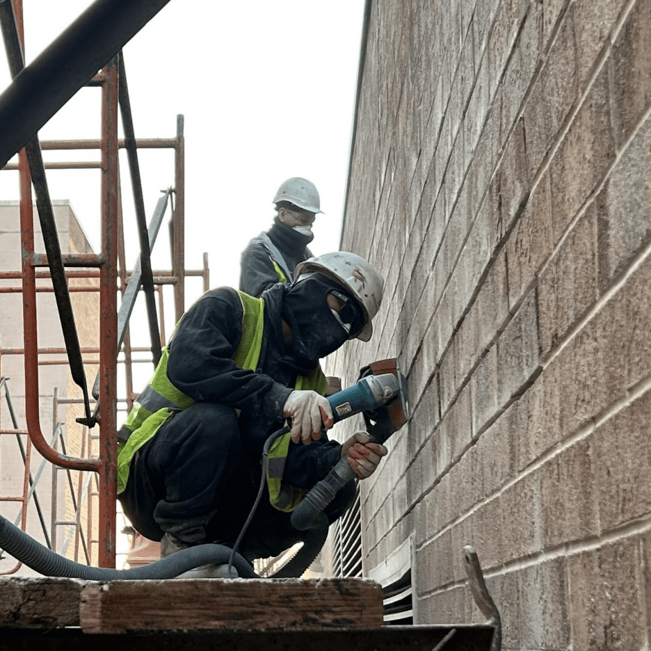 Workers repointing brick wall joints with fresh mortar on a construction site in Alexandria