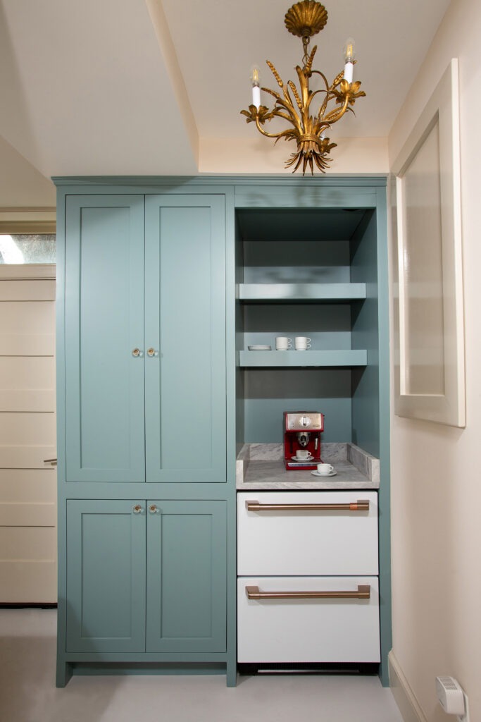 Inset blue built-in cabinetry with flush cabinet doors, open shelving, marble counter, and appliance drawers.