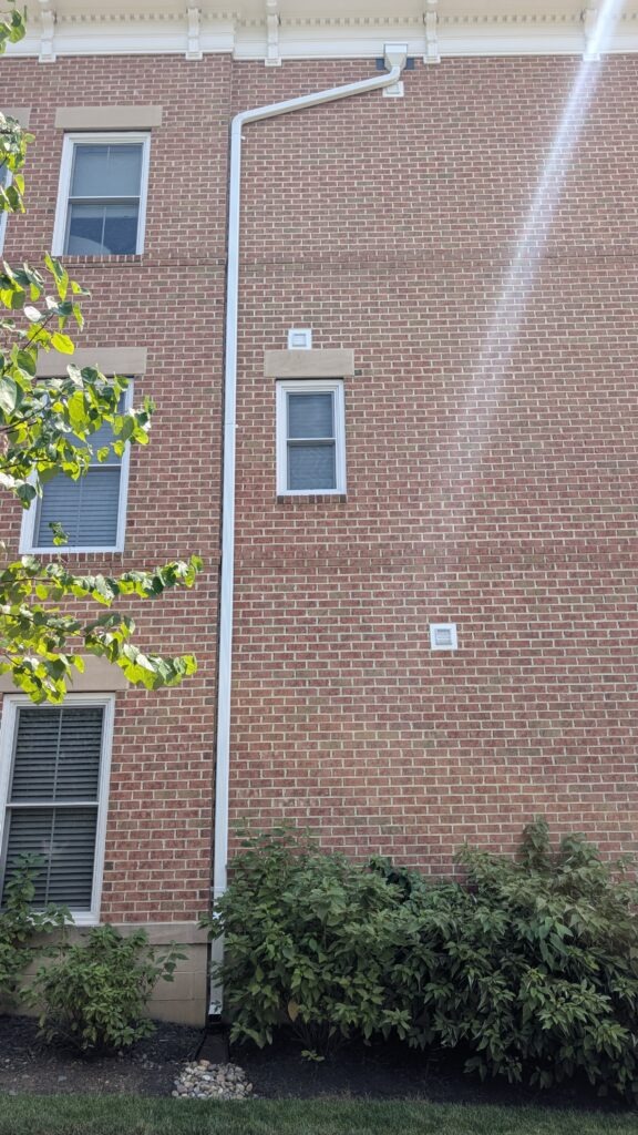 A clean, single downspout run on brick, no offsets, no exposed fasteners fighting the mortar joints.